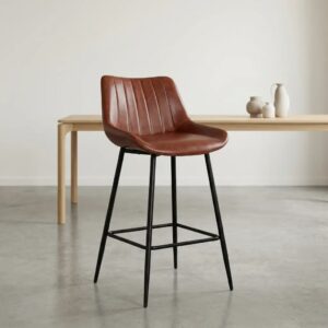 Cognac brown leatherette barstool with vertical channel-tufted low backrest, contoured bucket seat, black tapered steel legs, and integrated footrest crossbars.