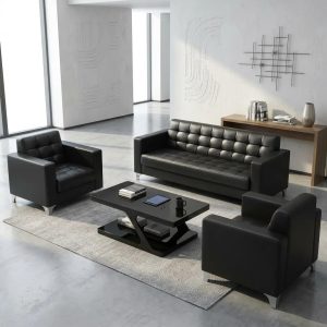 "5-seater black leatherette reception sofa set with tufted grid seats, square armrests, chrome L-shaped corner feet, and matching glass-top coffee table.