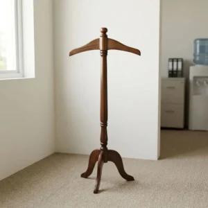 Vertical wooden coat hanger suit valet stand in dark walnut finish with top contoured jacket hanger, turned spindle center post, and three-legged tripod base.
