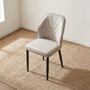 Beige faux leather dining chair with fan-stitched quilted backrest, padded seat cushion, and black tapered metal legs.