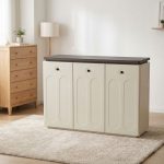 Off-white 3-door shoe storage cabinet with dark wood-grain top, arch-embossed door panels, and circular black recessed pull handles.