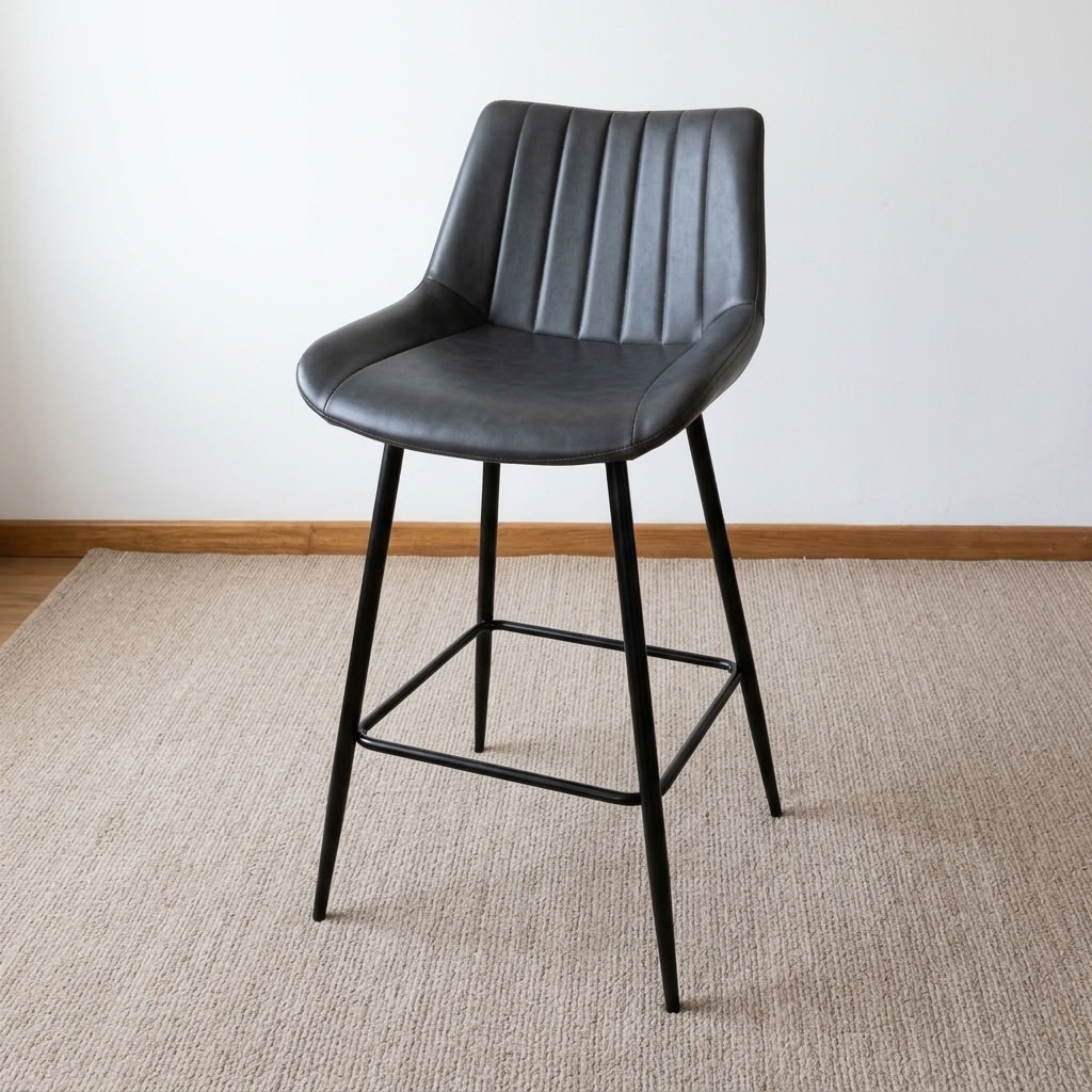 Gray leather counter barstool with vertical channel-stitched backrest, bucket seat, black metal tapered legs, and integrated footrest crossbars.
