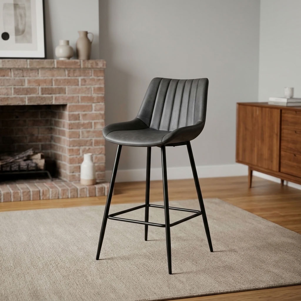 Gray leather counter barstool with vertical channel-stitched backrest, bucket seat, black metal tapered legs, and integrated footrest crossbars.